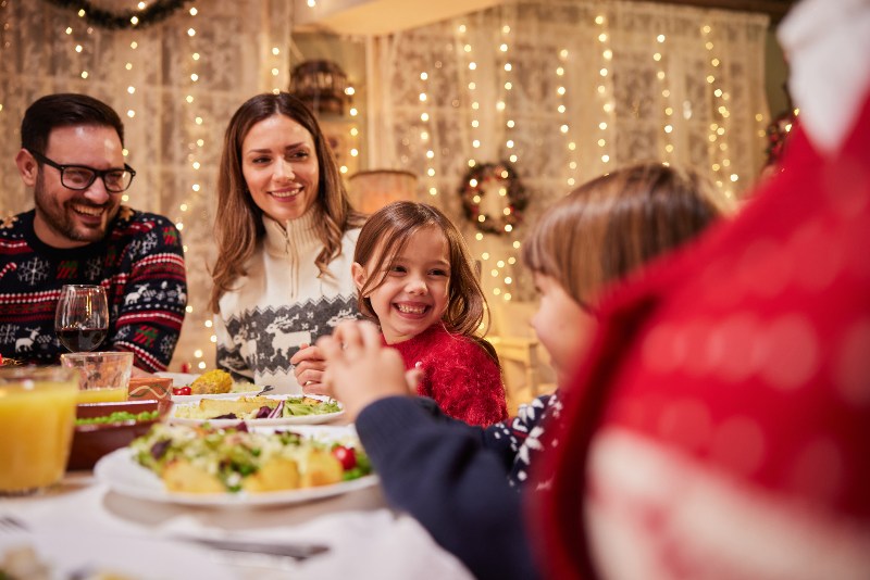 A group of people with kids smiling at a holiday meal by the Law Offices of Robert E. O’Connor