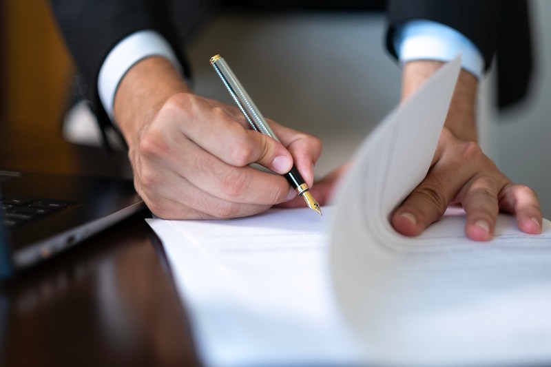 Man signing papers for an estate plan by the Law Offices of Robert E. O’Connor