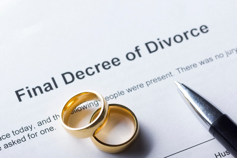 Wedding rings and a pen sitting on top of a final decree of divorce by the Law Offices of Robert E. O’Connor